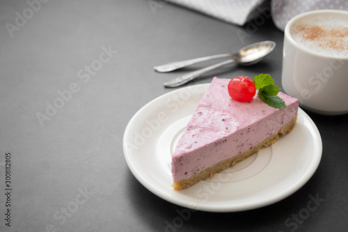 Cheesecake slice with berries and coffee cup, pink cheesecake isolated on dark background, dessert or breakfast. Sweet food.