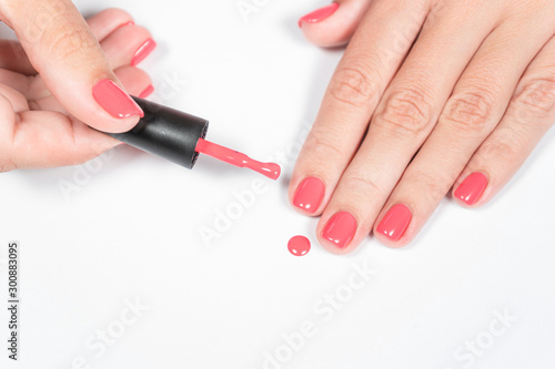 Closeup top view of woman holding brush wet from modern trendy bright gel nailpolish. Fingernails with fresh manicure. Horizontal color photography.