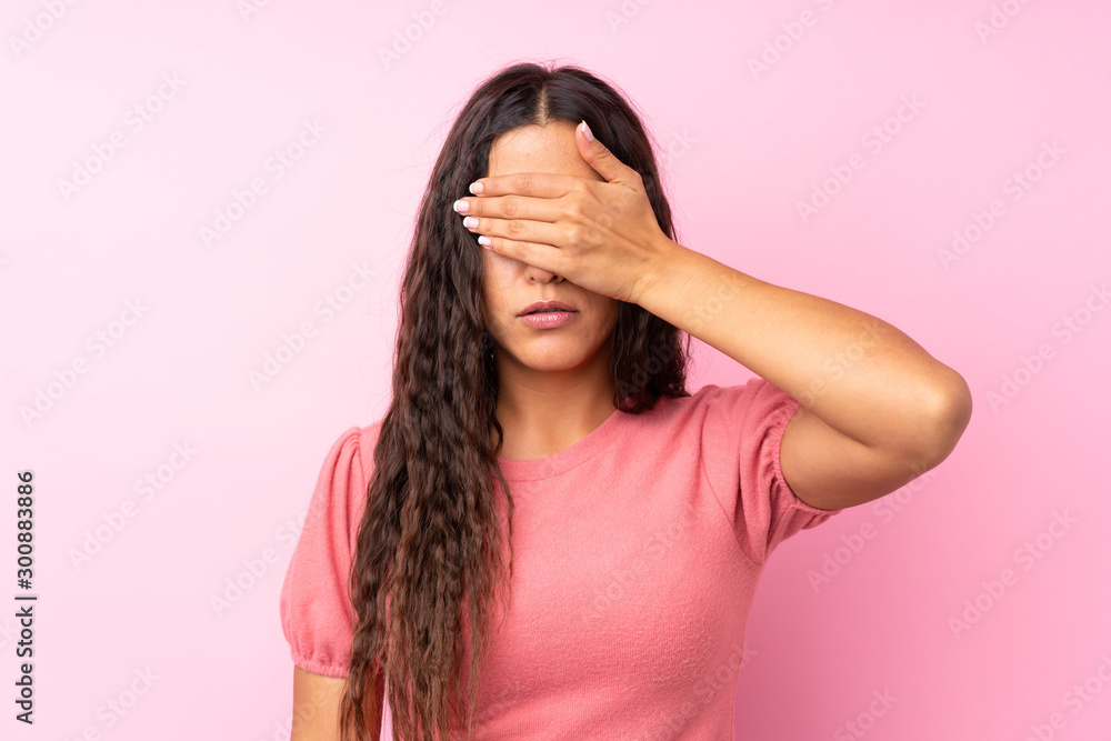 Young woman over isolated pink background covering eyes by hands Young woman over isolated pink background covering eyes by hands