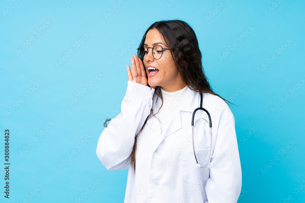 Young doctor woman over isolated blue background shouting with mouth wide open Young doctor woman over isolated blue background shouting with mouth wide open