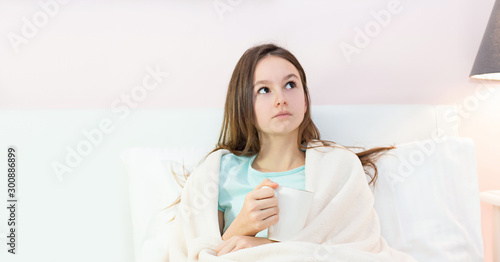 Teen girl lying in bed with a high fever