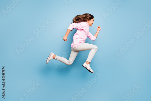 Full length body size photo of cheerful side profile positive crazy excited casual preteen wearing pink pants trousers footwear hurrying for discount isolated over pastel blue color background