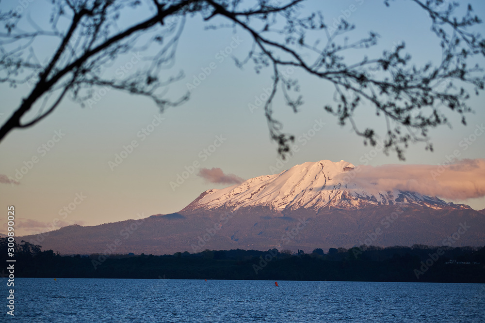 The Llanquihue lake with the magnificent Calbuco volcano and the moon. View from Puerto Varas near Puerto Montt, Chile.