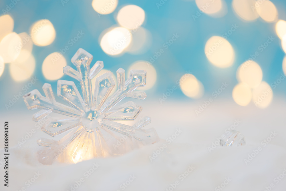 Close-up snowflake with defocused lights against blue background. Christmas greeting card. Christmas or New Year celebration concept. Copy space