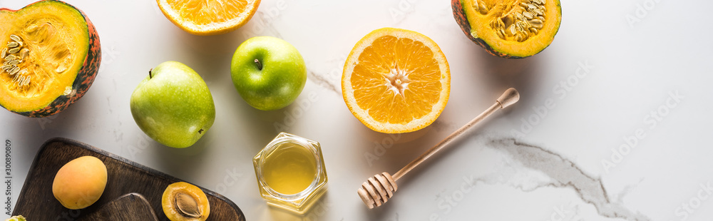 panoramic shot of cutting boards with pumpkin, orange, apricots and honey on marble surface panoramic shot of cutting boards with pumpkin, orange, apricots and honey on marble surface