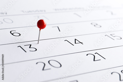 Red pin on a date on a calendar closeup. Important date. Place for text. Planning concept.