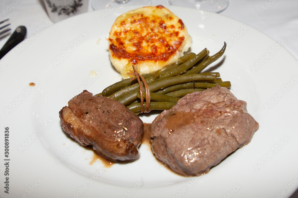 Steak duck fried smashed potatoes and green beans in a white plate restaurant table