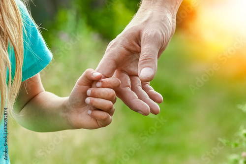hands of parent and child in nature photo
