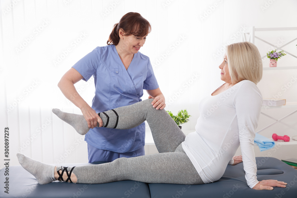 Obraz premium Close-up of famale physiotherapist massaging the leg of patient in a physio room.