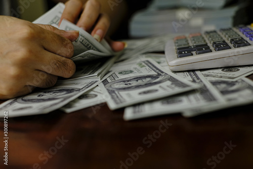 Businessmen women counting money on a stack of 100 US dollars banknotes