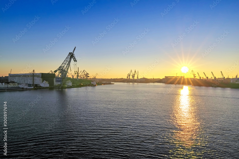 Sunrise in the sea cargo port, view of the moorings with cranes
