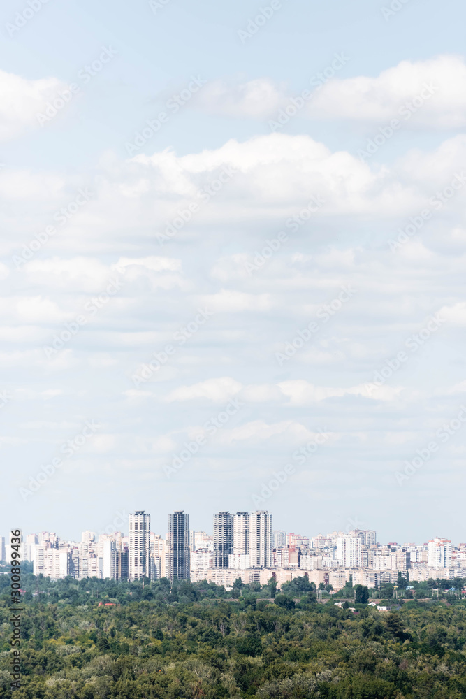 Urban scene with trees in city park, skyscrapers and buildings