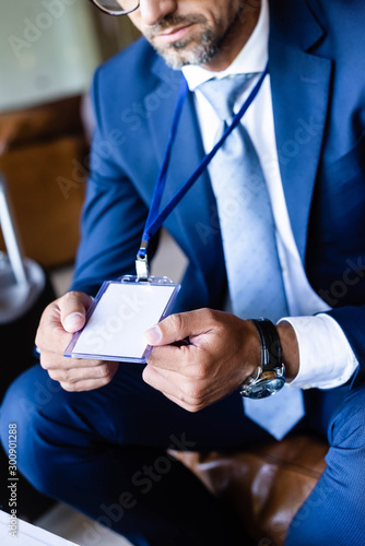 cropped view of man in formal wear holding badge with copy space