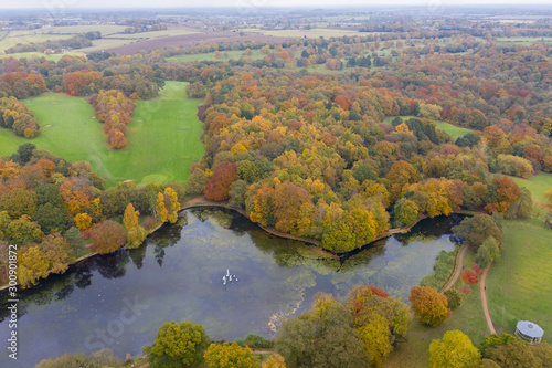 Aerial photo in autumn showing the beautiful autumn fall colours of a park in Leeds known as Roundhay Park in West Yorkshire UK, showing a typical British park and woods along side a lake.