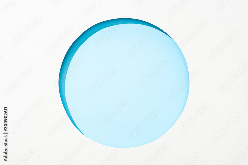 cut out round hole in white paper on light blue colorful background