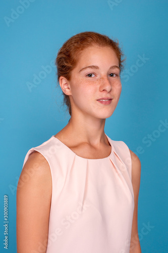 Studio shot of a attractive girl teenager with red hair against blue background