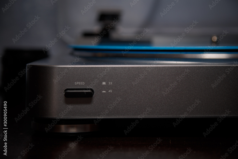 Modern vinyl record player. The blue vinyl record is played on the home player. Small depth of field. Dark, atmospheric photo. Modern vinyl record player. The blue vinyl record is played on the home player. Small depth of field. Dark, atmospheric photo.