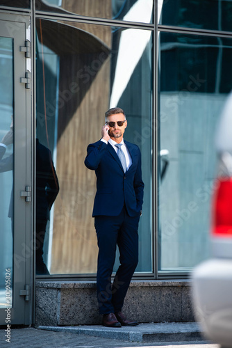 Foto handsome man in suit and glasses with hand in pocket talking on smartphone