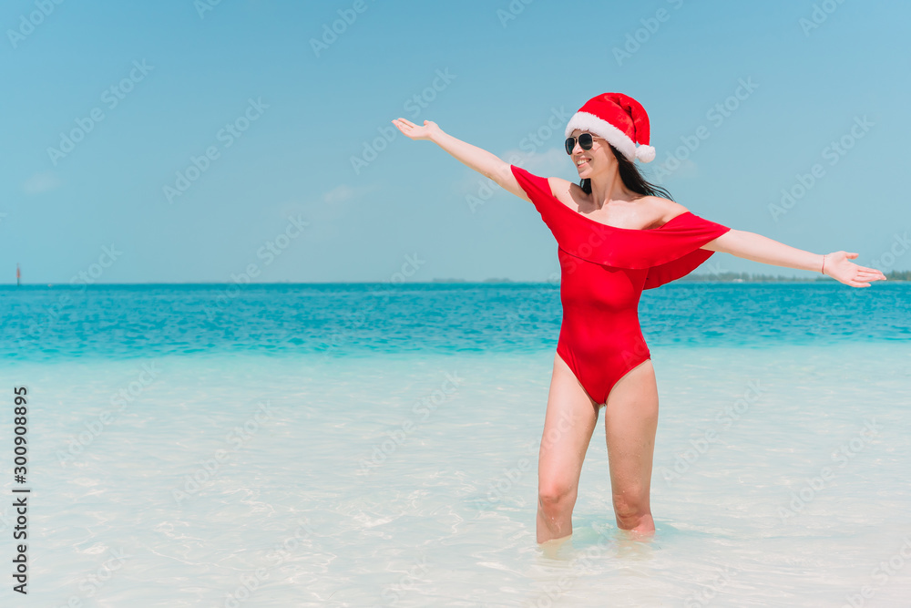 Young woman in Santa Hat walking spread her hands on white sandy beach Young woman in Santa Hat walking spread her hands on white sandy beach