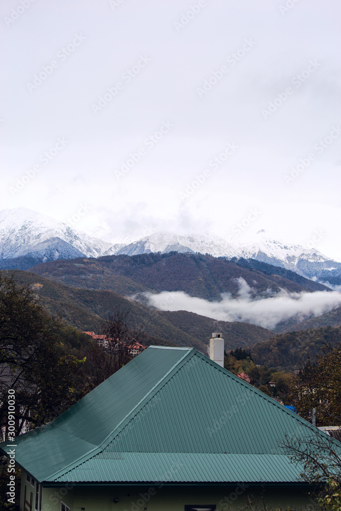 Fog in the mountains against the background of peaks with snow in the fall in Sochi, Russia.