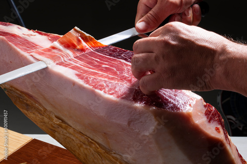 jamón serrano, manos cortándolo con cuchillo. Serrano ham, hands cutting it with a knife. photo