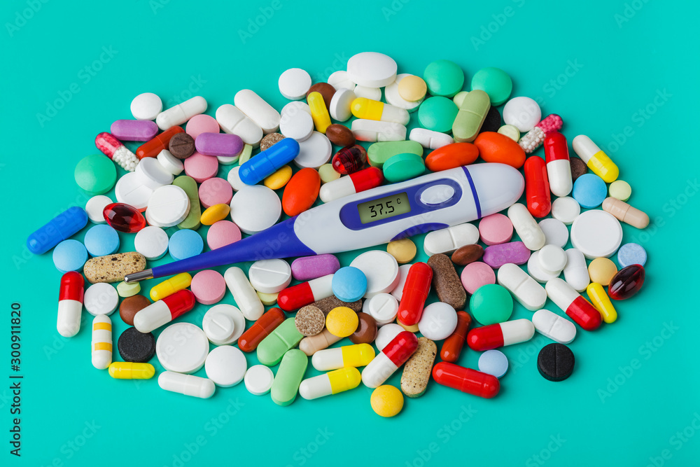 Pills and electronic thermometer (37.5 degrees) - medical background