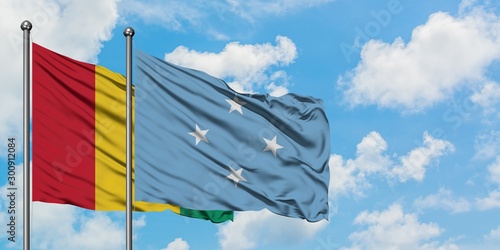 Guinea and Micronesia flag waving in the wind against white cloudy blue sky together. Diplomacy concept, international relations.