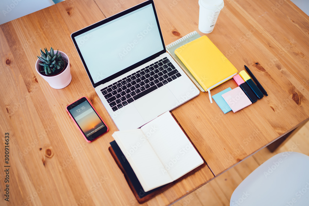 Opened laptop with white screen and office supplies with smartphone on wooden table Opened laptop with white screen and office supplies with smartphone on wooden table