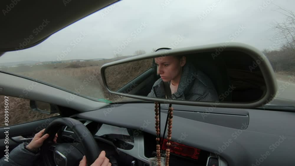 Cinematic Rear mirror view of beautiful young woman driving her car on the misty road Cinematic Rear mirror view of beautiful young woman driving her car on the misty road