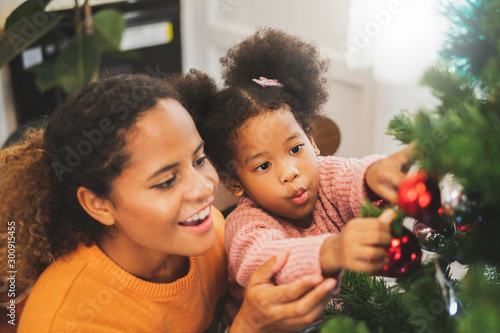 Black african mother and her cute daughter decorating christmas tree for christmas and happy new concept
