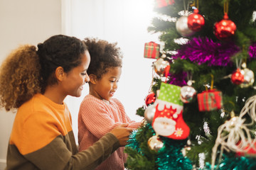 Black african mother and her cute daughter decorating christmas tree for christmas and happy new concept