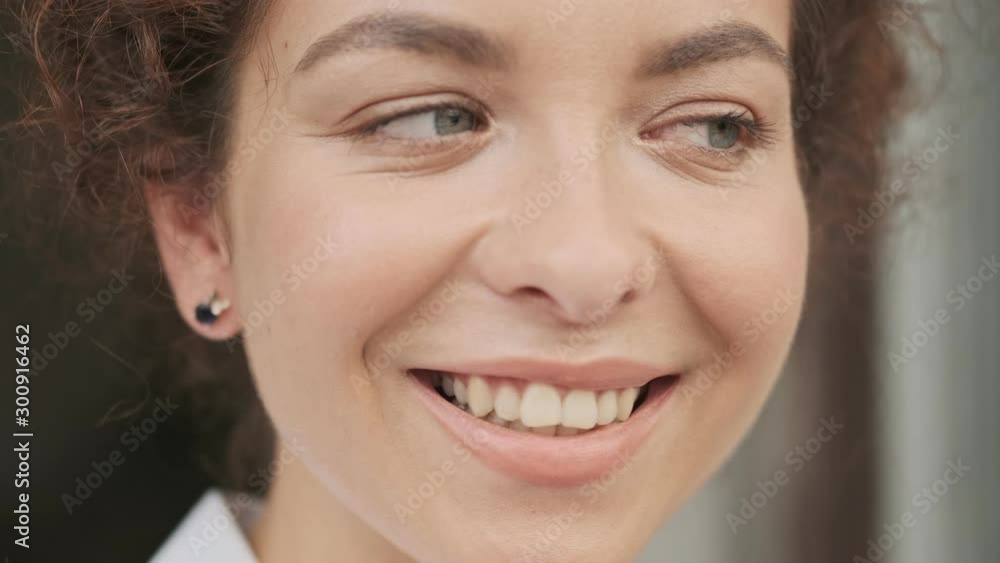 Cropped view of attractive lovely young redhead woman in white shirt biting her lip and looking flirty while looking at the camera outdoors Cropped view of attractive lovely young redhead woman in white shirt biting her lip and looking flirty while looking at the camera outdoors