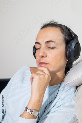 Young Spanish woman listening to music at home with headphones
