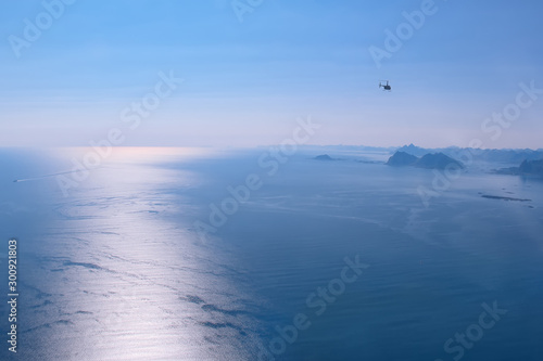 Polar day in the Norwegian sea. View from the cockpit of the helicopter on the water surface of the Norwegian sea. The glow of the setting sun on the sea surface.