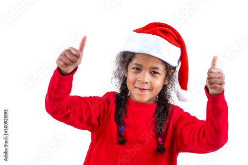 Little girl in a Santa Claus hat shows two thumbs on a white background photo
