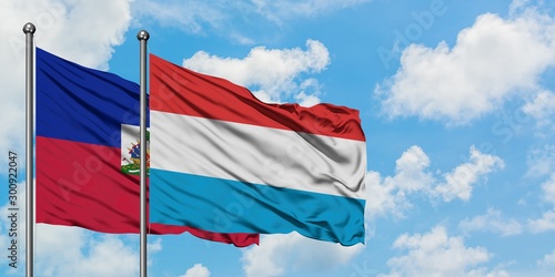 Haiti and Luxembourg flag waving in the wind against white cloudy blue sky together. Diplomacy concept, international relations.