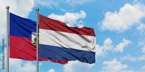 Haiti and Netherlands flag waving in the wind against white cloudy blue sky together. Diplomacy concept, international relations.
