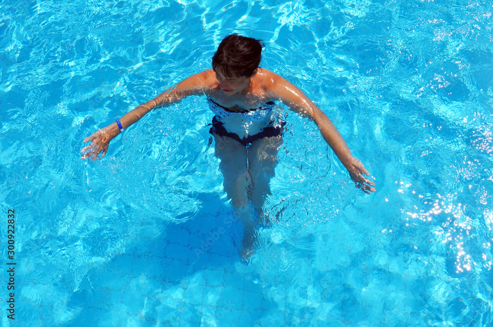 Aerial top view of woman in swimming pool water from above
