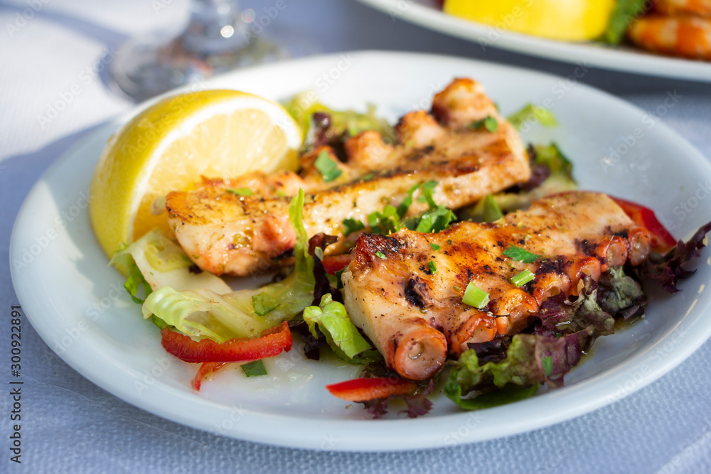 Fried octopus on plate with slice of lemon in taverna in Greece Fried octopus on plate with slice of lemon in taverna in Greece