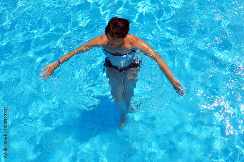 Aerial top view of woman in swimming pool water from above