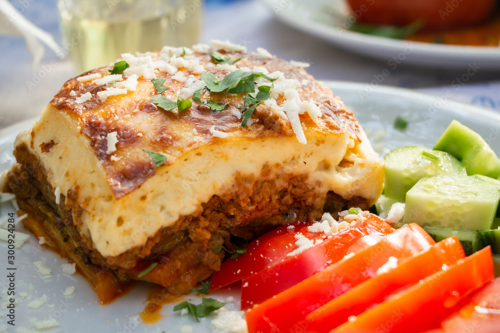 Greek traditional moussaka on a white plate served in taverna, Greece Greek traditional moussaka on a white plate served in taverna, Greece