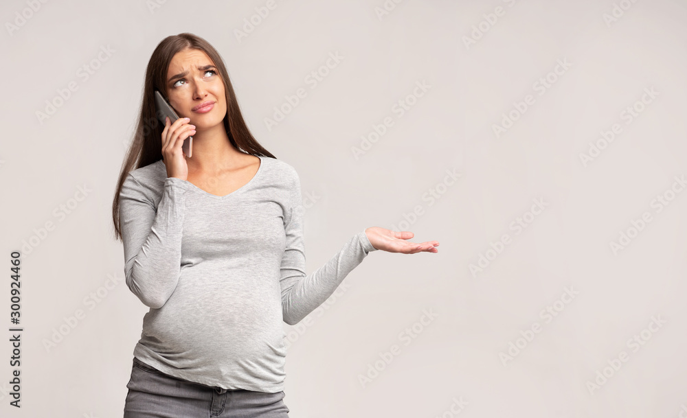 Discontented Pregnant Girl Talking On Phone Standing Over Gray Background Discontented Pregnant Girl Talking On Phone Standing Over Gray Background