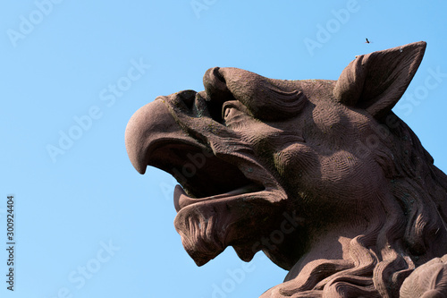 sculpture: brown Griffin head against the sky.