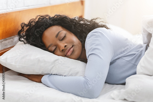 Peaceful afro girl sleeping in bed in morning