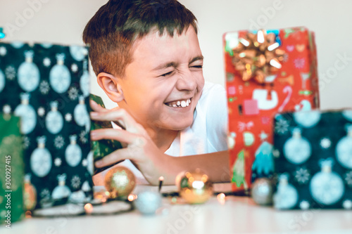 Young boy preparing gifts for the Christmas. Unpacking presents on the table. Winter holidays celebrating concept.