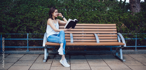 Young Asian focused brunette reading book and sitting on bench © BullRun
