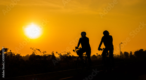 Cyclists on the road backlit at sunrise in the morning.