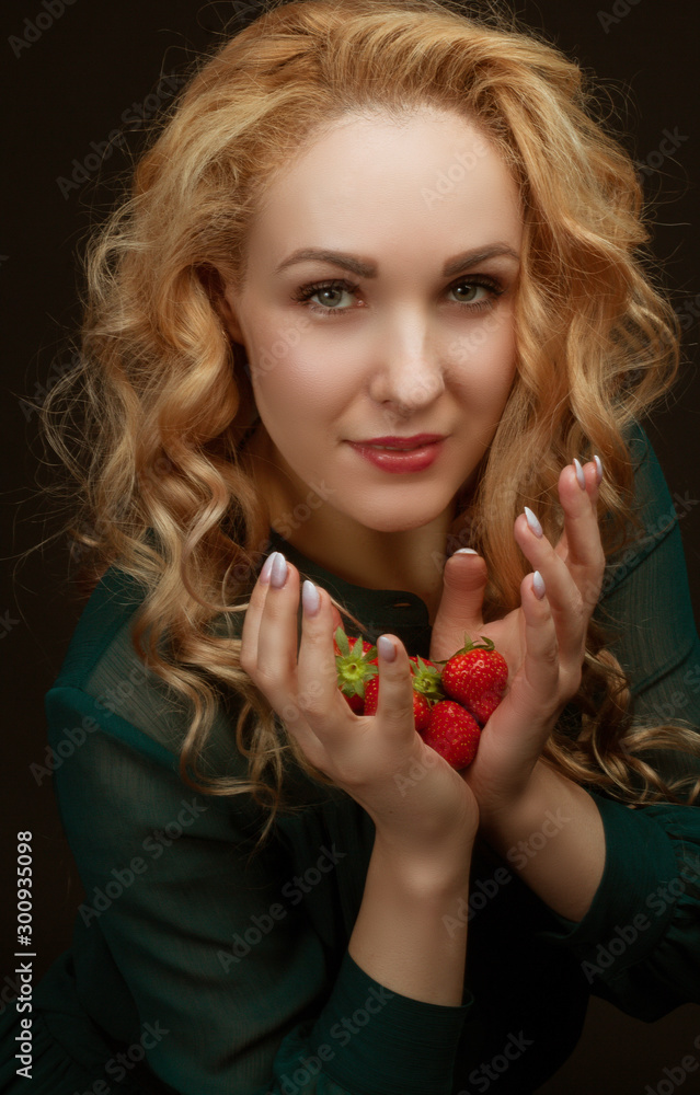 Beautiful resilient young girl holding a strawberry. Portrait in the studio background Beautiful resilient young girl holding a strawberry. Portrait in the studio background