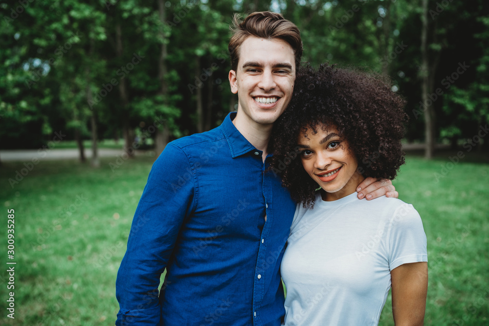 Portrait of millennials engaged couple at the park - A man and a woman hug each other Portrait of millennials engaged couple at the park - A man and a woman hug each other