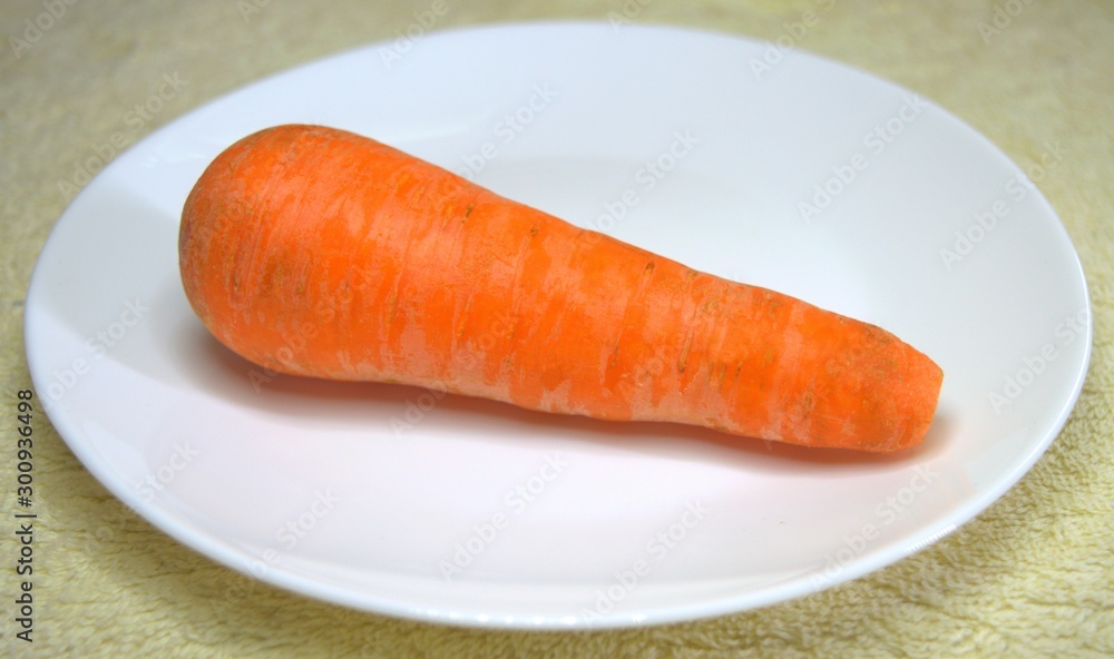 Carrots. One. Whole for cooking different dishes. On a white plate. Vegetables. Food. Carrots. One. Whole for cooking different dishes. On a white plate. Vegetables. Food.